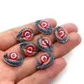Close-up of colorful evil eye printed natural cowrie shell beads held in a hand - Pack of 20 (9x19mm) / Pink Blue and Yellow Evil Eye Pattern (3)