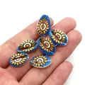Handheld view of six bohemian blue hand-painted spiral seashells with floral motifs - 9x19mm (20 Pieces/Pack) / No. 2 (Blue Sunflower Pattern)