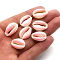 Detailed view of hand holding small pink and white candy-colored seashell beads for DIY - Light Pink And White