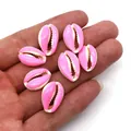 Pink glazed cowrie shell beads for DIY jewelry making displayed on a palm for scale - Pink and White