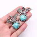 Close-up of vintage viking dragon pendants holding turquoise stones in silver finish - 43x43mm / Blue Turquoise