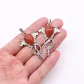 Detailed view of silver wing key pendants featuring sparkling orange goldstone inlay - Gold Sandstone