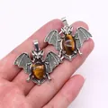Macro detail of bat-shaped Tiger Eye stone pendants with antique silver alloy wings - Tiger's Eye