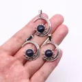 Three celestial sun and moon pendants with blue sand stone inlay held by a hand - Pendant Only (22x29mm, Without Chain) / Blue Sandstone