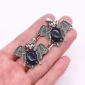 Detailed close-up of bat-shaped alloy pendants with blue sandstone inlay in hand - Blue Sandstone