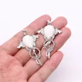 Gothic silver angel wing key pendant with white turquoise stone held in hand - Howlite