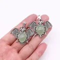 Macro view of bat-shaped vintage silver alloy pendants with green gemstone inlays - Green Aventurine