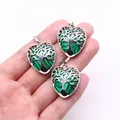 Three heart-shaped life tree pendants with green malachite texture held in hand for scale - Malachite