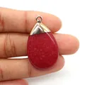 Detail of red teardrop natural stone pendant with gold clasp held by fingers for size - Carnelian