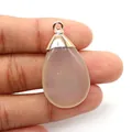 Macro view of teardrop natural stone pendant with silver clasp held by hand - Agate