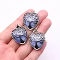 Silver tree of life heart pendant with blue natural stone held in hand on white background - Blue Spot Stone