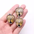 Yellow crystal heart pendant with silver tree of life filigree in a hand for size scale - Topaz