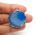 Detalle del colgante de rebanada de ágata azul con bordes dorados sostenido por dedos - Colgante de Ágata Azul (N.º 3)