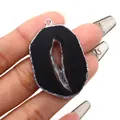 Irregular black druzy agate slice pendant with silver electroplated edge being held - Black