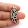 Feather shaped dalmatian jasper pendant with gold plated edges held in hand - Dalmatian Jasper