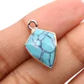 Handheld view of a shield-shaped turquoise pendant with golden gold-plated edges - Blue Turquoise