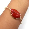 Macro shot of an irregular gold-plated bracelet featuring a natural oval red jasper gemstone - Red Jasper