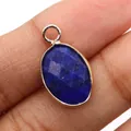 Makroaufnahme des blauen Goldfluss-Ovalanhängers mit vergoldetem Rand in den Fingern - Lapislazuli