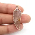 Pendentif ailes en pierre naturelle rose avec bordure dorée tenu par les doigts - Pierre Translucide Rose (10)