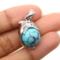 Detailed view of a dolphin pendant holding a blue turquoise bead held by hand - Dolphin Shape / Blue Turquoise