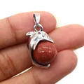 Macro view of a silver dolphin pendant featuring a reddish-brown goldstone bead inlay - Dolphin Shape / Gold Sandstone