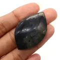 Macro shot of labradorite marquise leaf stone with blue flash held in fingers - 26x41mm