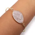 Gold plated open cuff bracelet with an oval rose quartz stone shown on a wrist - White Crystal