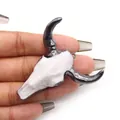 Macro detail of a vintage acrylic bull skull pendant held in hand for scale and texture - White Black Horns (No. 3)