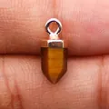 Macro-opname van tijgeroog zeshoekige hanger met verzilverde sluiting op een vingertop - Tijgeroog