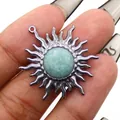 Detail of silver sun flower pendant with light turquoise stone held between fingers - Amazonite