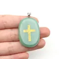Gros plan d'un pendentif en aventurine verte avec un symbole de croix dorée gravée - Aventurine Verte