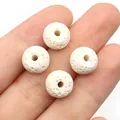 Close-up of four white lava stone diffuser beads with porous texture held on a hand - No. 1 (7x10mm) / Off White