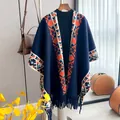 Mantella in maglia etnica con motivi geometrici e frange appesa a una gruccia in legno - Blu
