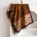 Detail of floral patterned pashmina shawl with caramel leaf design and tassel fringe edge - 180cmx65cm / Brown