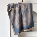 Detail shot of a soft faux cashmere scarf with blue sunflower prints and fringed edges - 185cm / Blue