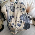 Sciarpa jacquard beige e blu con motivi floreali e nappe su un divano morbido - Blu Beige