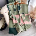 Close-up of thick winter scarf with large floral patterns and neat edge stitching - Green