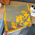 Primer plano de bufanda de lirios amarilla y gris con flecos en mesa de madera - 185cm / Amarillo