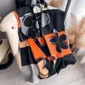 Winter scarf with orange floral cashmere feel and fringe edge draped on an armchair - Black