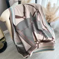 Pink cashmere blend horse print shawl with fringes and equestrian patterns on a sofa - Pink