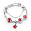 Macro detail of stainless steel charm bracelet with red crystals and love engraving - Red