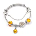 Detailed shot of a silver beaded bracelet featuring orange gemstones and heart charms - Yellow