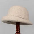 Elegant beige wool cloche hat with ribbon bow detail on a wooden display stand - M (56-58cm) / Beige