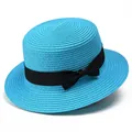 Detalle de sombrero de paja azul con copa plana y cinta negra sobre fondo blanco - Azul lago
