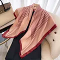 Detail of silk-like pink and burgundy geometric patterned square scarf on a wooden hanger - Khaki