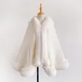 Detailed close-up of white knitted poncho with thick faux fur trim on a mannequin stand - White