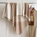 Detalle de la elegante bufanda geométrica beige y blanca con flecos y suave textura de punto - Caqui