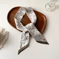 Détail d'un foulard en soie Paisley beige élégamment placé sur un plateau en bois - Floral Paisley Beige Marron (V-22)
