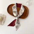 Detail of a silk scarf with green fern print and burgundy lining on a wooden tray - Cream Fern Plant (D-4)