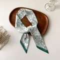 Vue détaillée d'un foulard long en soie avec motifs paisley verts sur un plateau en bois - Floral Paisley Blanc Vert (T-20)